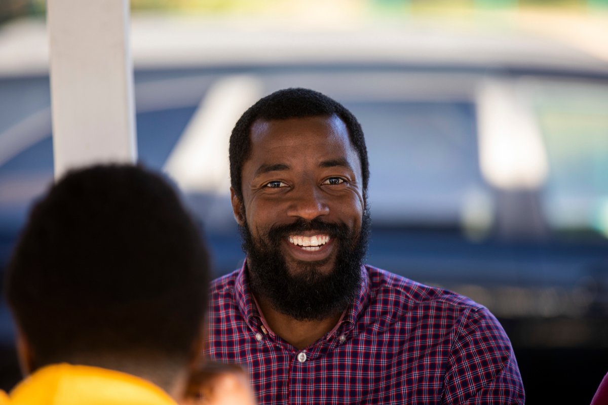 A male graduate student smiles at the camera at a department picnic